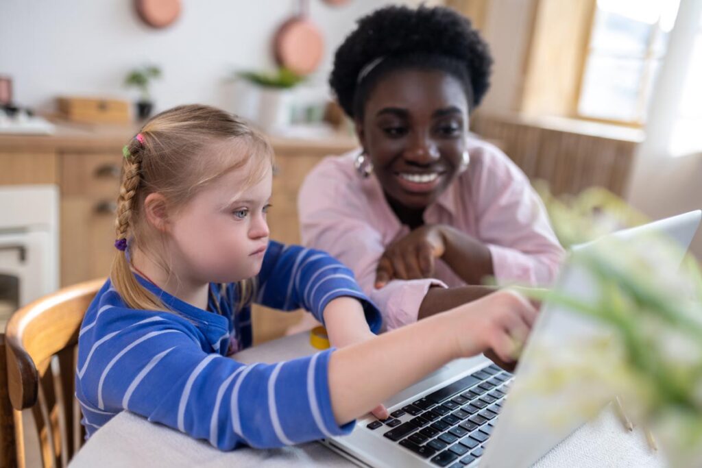 A girl with down syndrome having a lesson with her teacher and looking involved